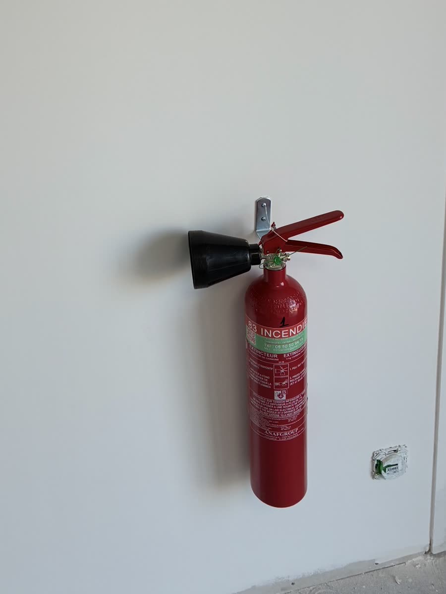 Extincteur CO2 fixé au mur sous son panneau de signalisation 83 incendie