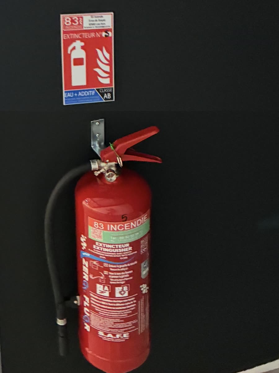 Extincteur 83 incendie et son panneau de signalisation, fixés sur un mur sombre